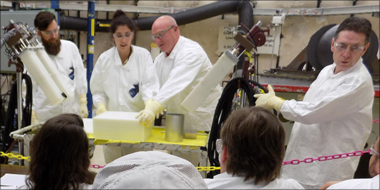 Photo. Students stack polyethylene plates and uranium foils under the instruction of David Hayes (Advanced Nuclear Technology, NEN-2, second from right) and Rene Sanchez (NEN-2, far right) at a criticality safety class.