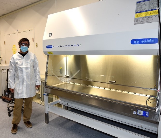 Researcher Ben Stein (C-PCS) stands in front of a hard-ducted biological safety cabinet designed for Risk Group-2 organisms and small quantities of radioactive materials. It represents a unique capability at LANL.